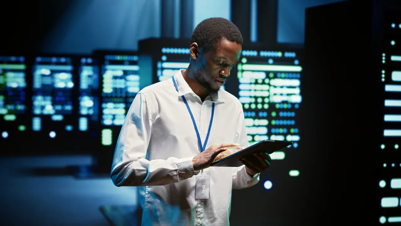Technician working with a tablet beside server equipment